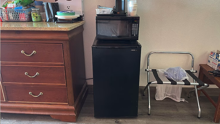 Mini fridge and microwave setup in a hotel room for storing and reheating carnivore diet foods like meat, eggs, and butter.