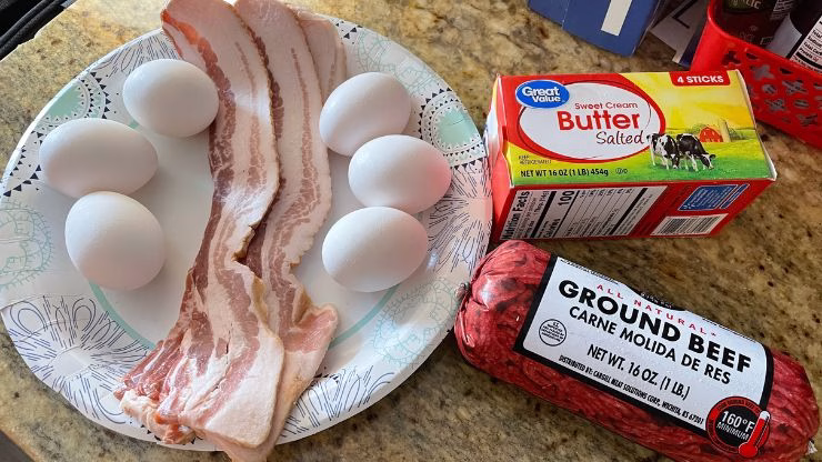 Ingredients for carnivore scramble: raw ground beef, bacon slices, eggs, and butter on a countertop.