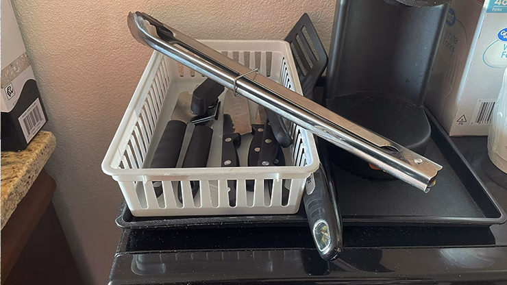 Minimal carnivore cooking utensils in a hotel room setup, including tongs, knives, and a can opener for preparing meat-based meals without a full kitchen.