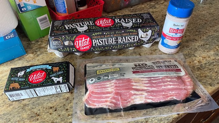 Ingredients for carnivore scrambled eggs, including eggs, bacon, butter, and salt
